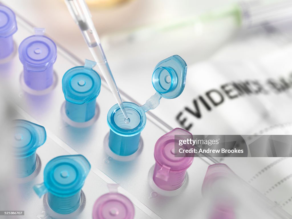 Pipetting DNA sample collected from crime scene into vial for forensic testing in laboratory