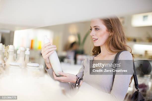 woman browsing products on display shelf - magasin cosmétique photos et images de collection