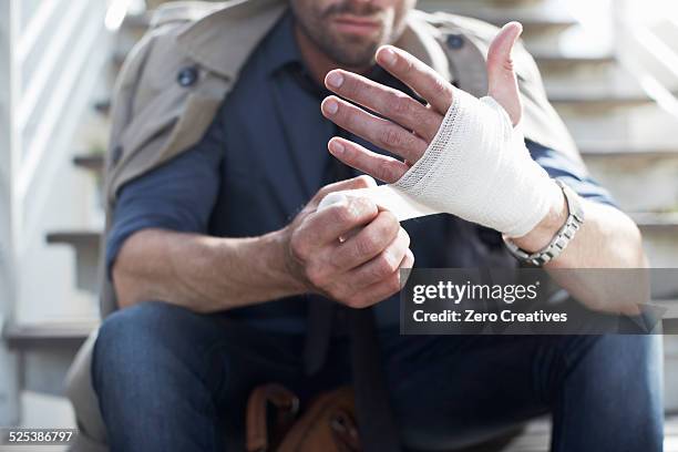 man bandaging hand on staircase - gauze stock pictures, royalty-free photos & images