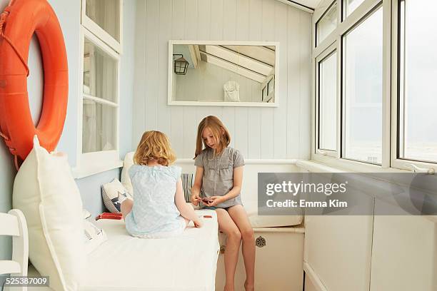 two sisters playing cards in holiday apartment porch - camber sands stockfoto's en -beelden