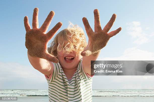 girl holding up sandy hands on breezy beach, camber sands, kent, uk - air child play stock-fotos und bilder