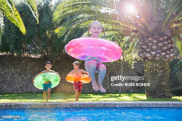 girl jumping with inflatable ring into garden swimming pool - ring swimming pool stock pictures, royalty-free photos & images