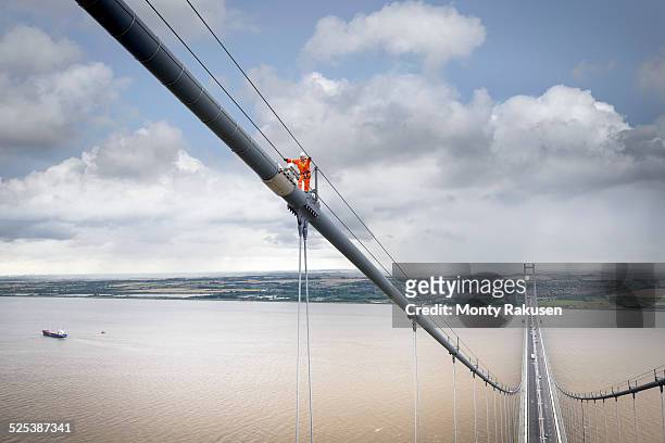 bridge worker walking on cable of suspension bridge. the humber bridge, uk was built in 1981 and at the time was the worlds largest single-span suspension bridge - humber bridge stock pictures, royalty-free photos & images