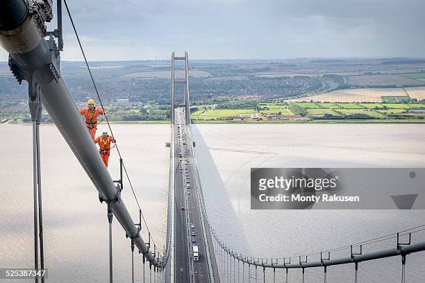 bridge workers walking on cable of suspension bridge. the humber bridge, uk was built in 1981 and at the time was the worlds largest single-span suspension bridge - humber bridge stock pictures, royalty-free photos & images