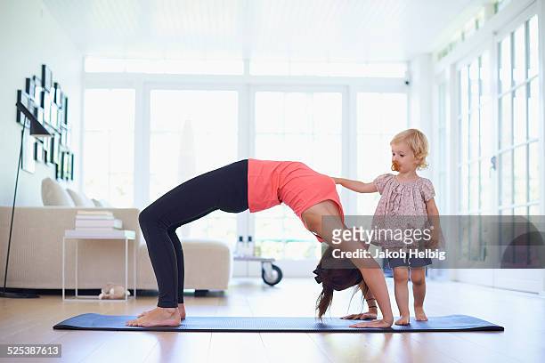 mid adult mother practicing yoga with curious toddler daughter - running shorts stock pictures, royalty-free photos & images