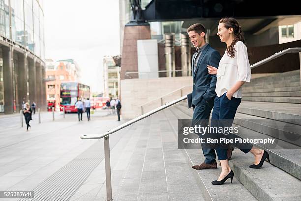 rear view of young businessman and woman chatting whilst walking down stairway, london, uk - down blouse ストックフォトと画像