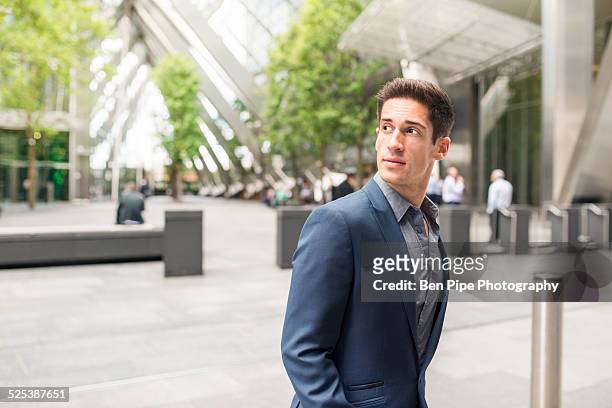 young businessman looking over his shoulder at broadgate tower, london, uk - looking over shoulder photos et images de collection