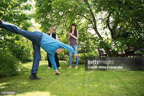 grandparents and granddaughter doing acrobatics in garden - cartwheel stock pictures, royalty-free photos & images