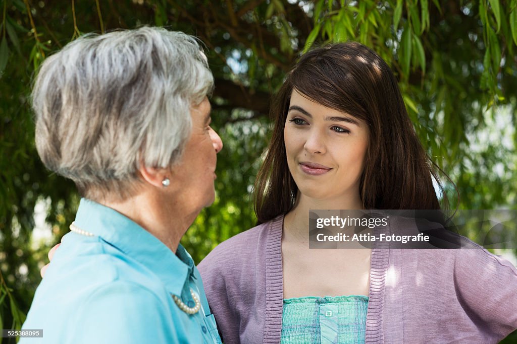 Grandmother and granddaughter having conversation in garden