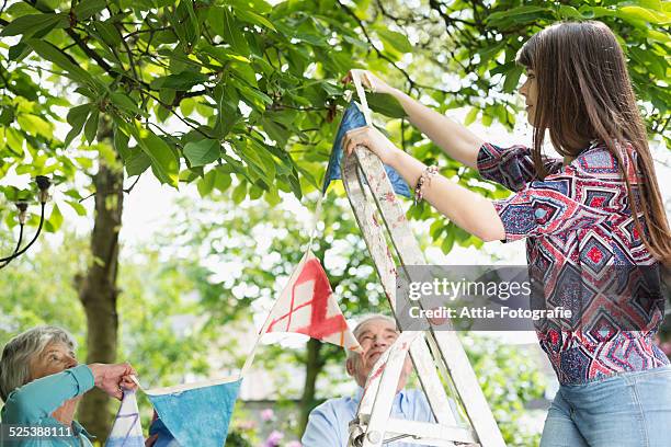 grandparents and granddaughter hanging up bunting - step ladder stock pictures, royalty-free photos & images