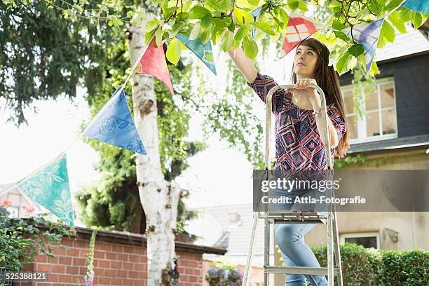 woman hanging up bunting - step stool stock pictures, royalty-free photos & images