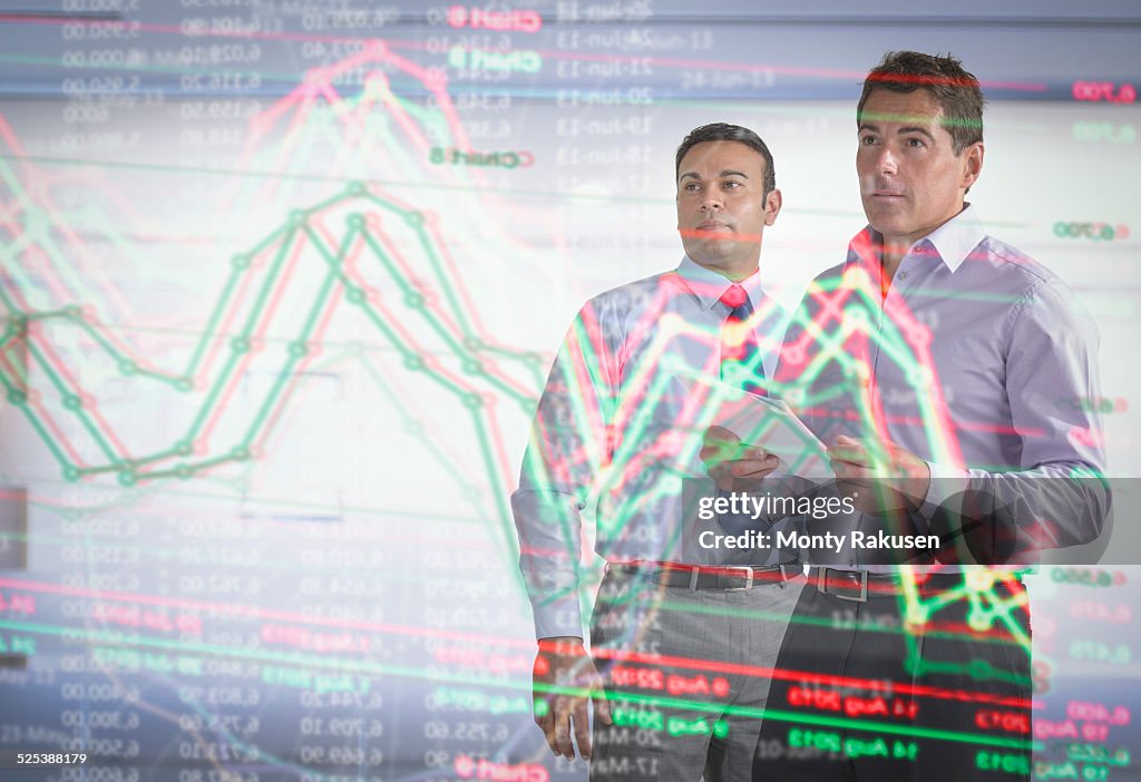 Businessmen inspecting graph on interactive futuristic display
