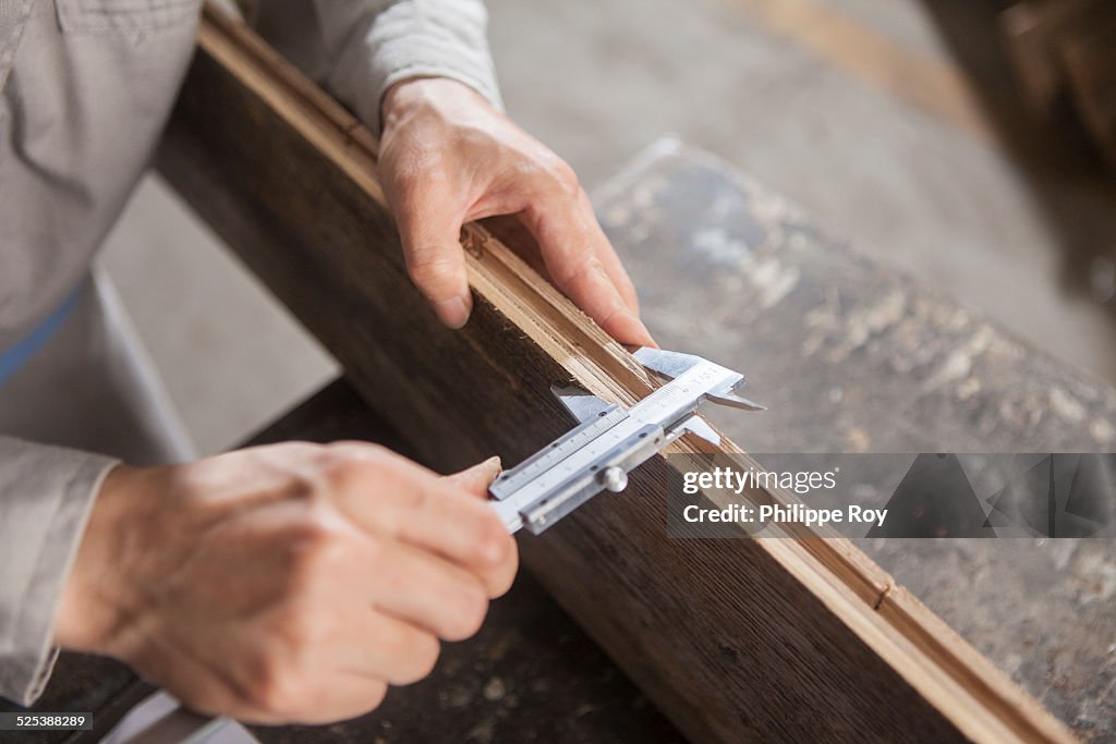 Carpenter measuring wood plank with vernier caliper in factory, Jiangsu, China