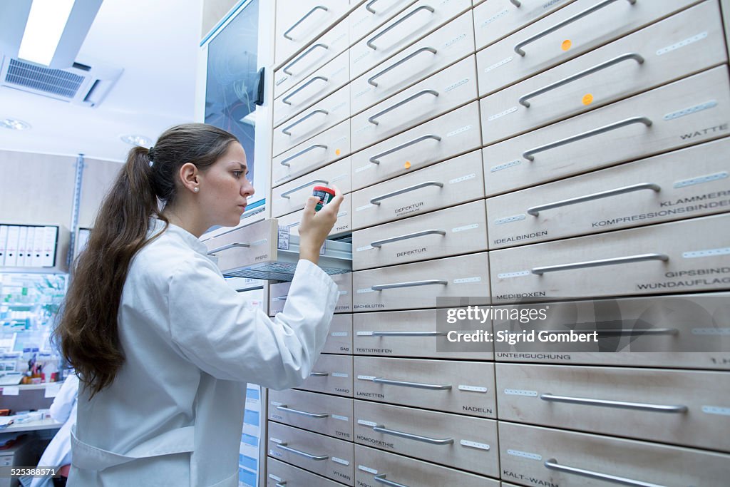 Pharmacist in pharmacy opening medicine file drawer