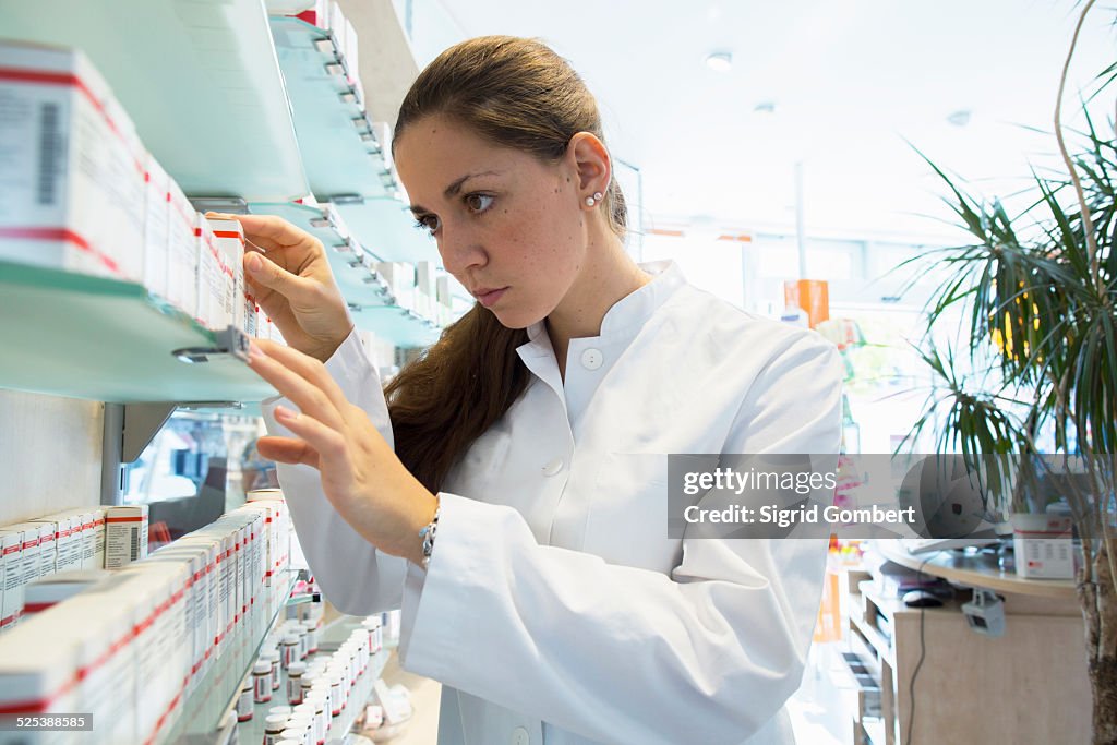 Pharmacist in pharmacy looking at medicine box