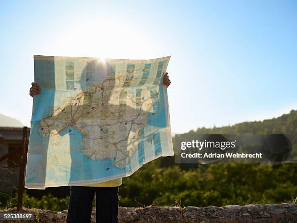 shadow of boy holding up a map, majorca, spain - instrumento de navegación fotografías e imágenes de stock
