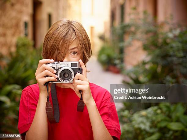 portrait of boy photographing village street using slr camera, majorca, spain - spiegelreflexcamera stockfoto's en -beelden