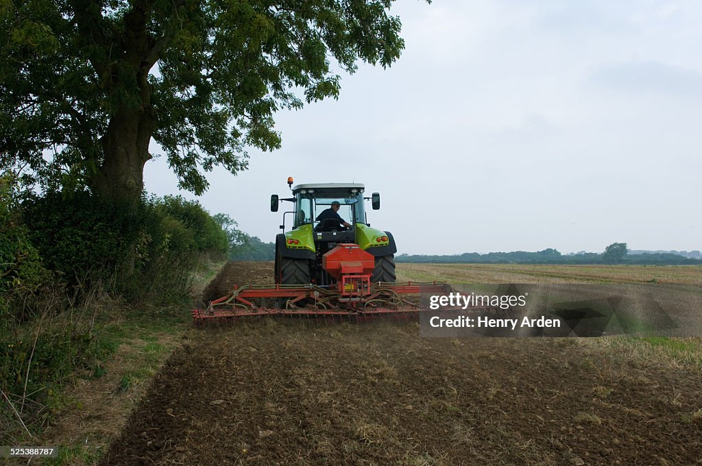 Farmer driving tractor and planting seed corn in field