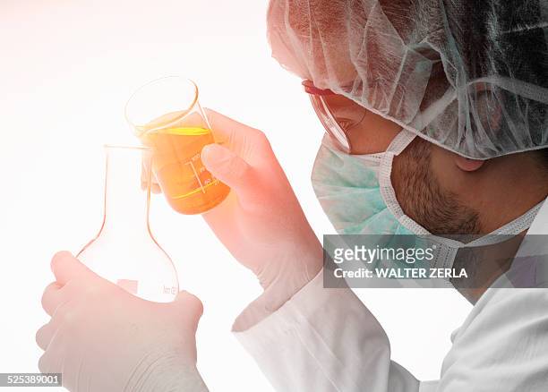 chemist pouring liquid from beaker into flask - chimiste photos et images de collection