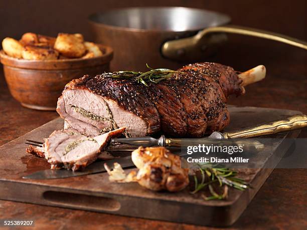 christmas dinner. roasted rosemary and garlic leg of lamb and roast potatoes - roasted fotografías e imágenes de stock