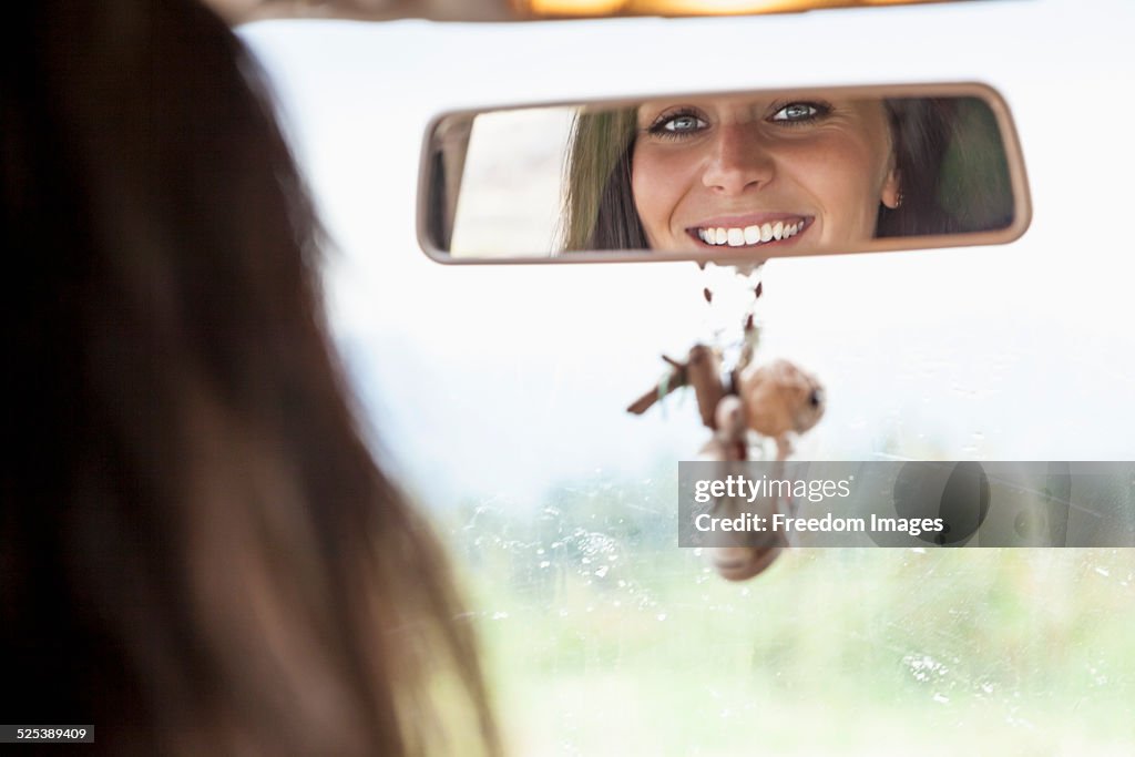 Young woman looking in rear view mirror