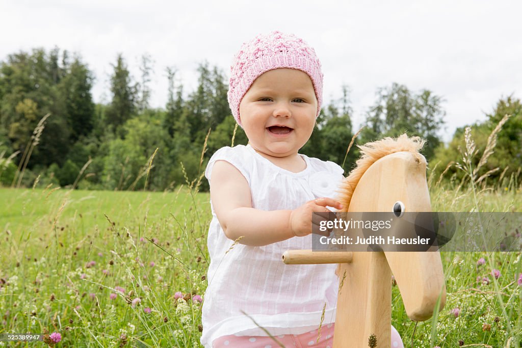Baby girl playing on hobby horse