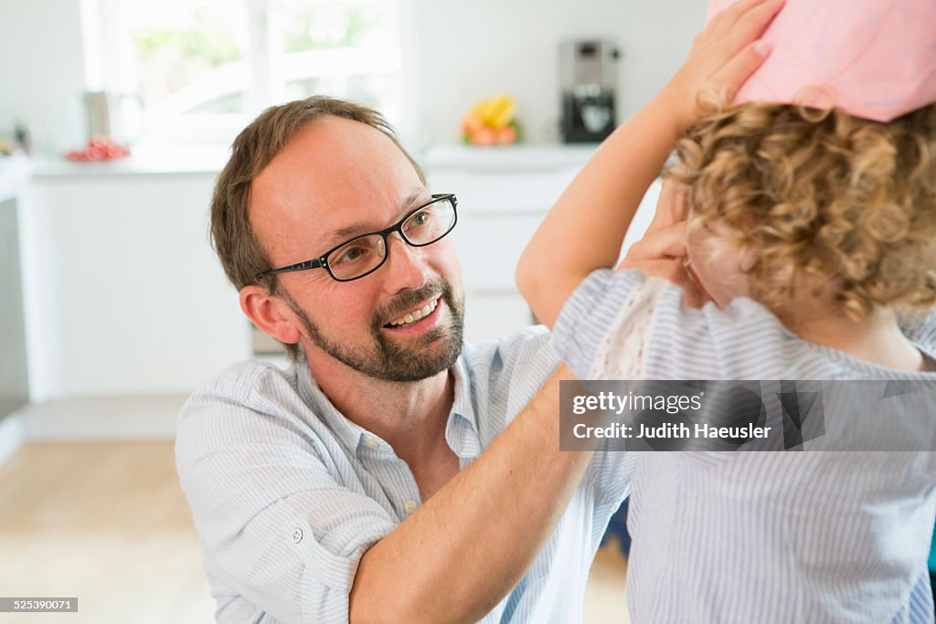 Girl trying on paper crown with father