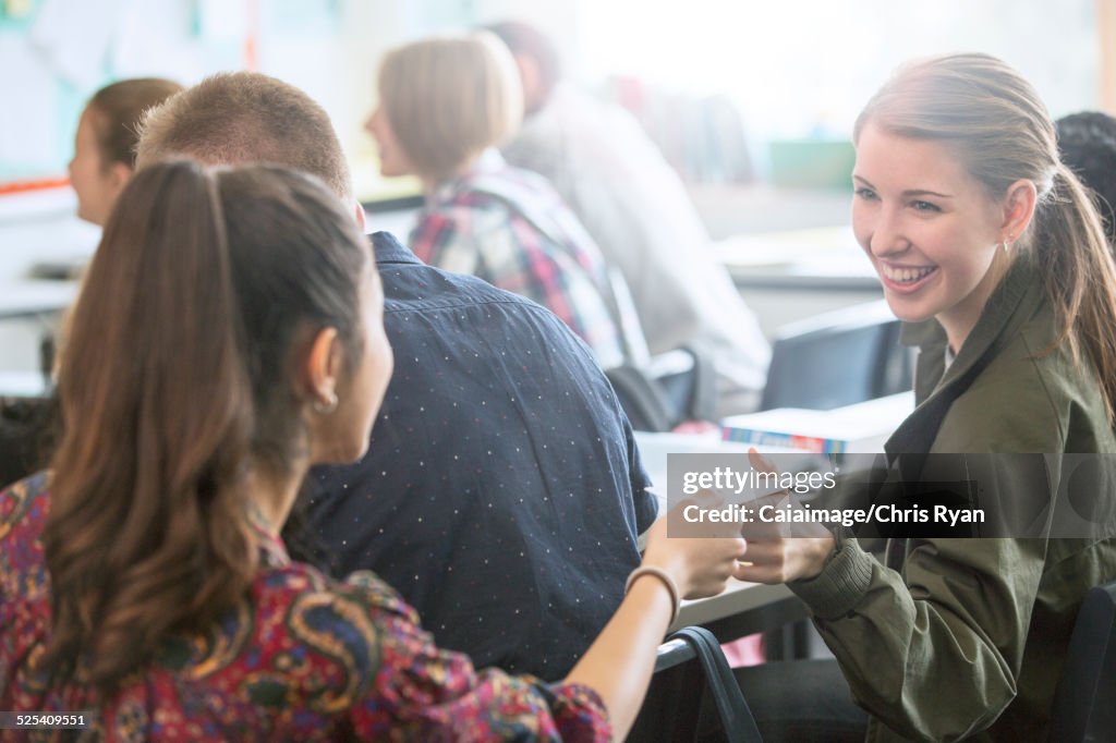 Smiling female students exchanging notes in classroom