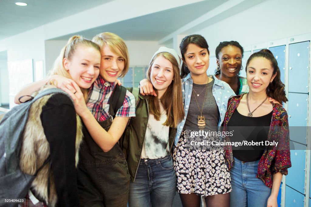 Group portrait of cheerful female students standing in locker room