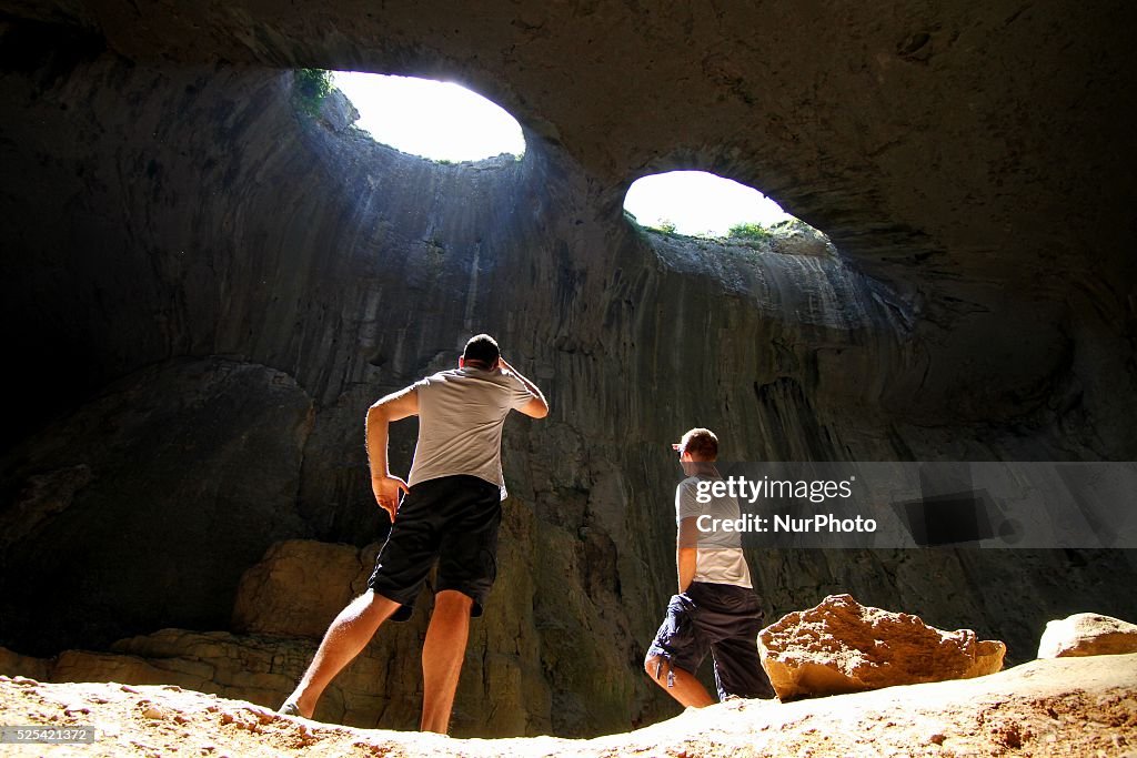 Prohodna Bungee jumpers jump over the Prohodna cave's entrance and tourists ...