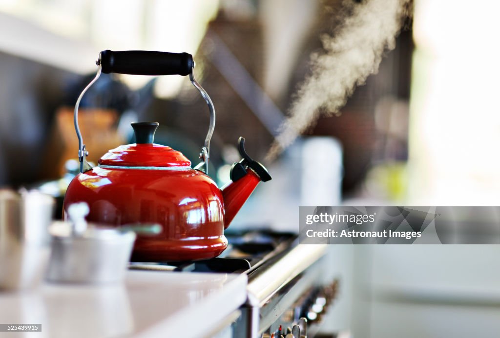 Bouilloire rouge à l’ancienne sur cuisinière avec de la vapeur qui sort