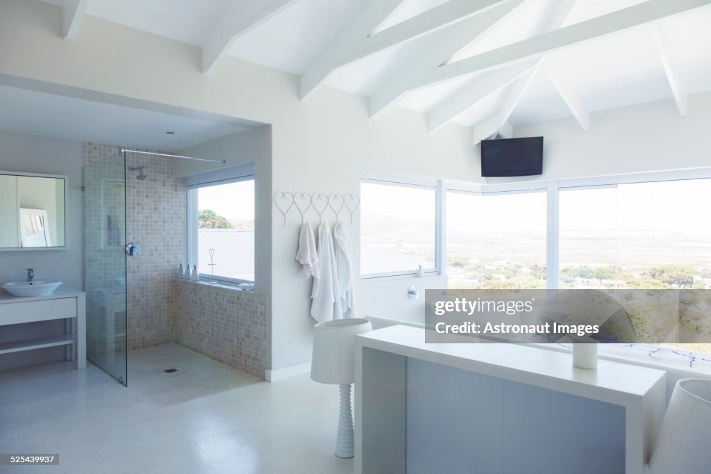 Modern white bathroom interior with large bathtub and shower area