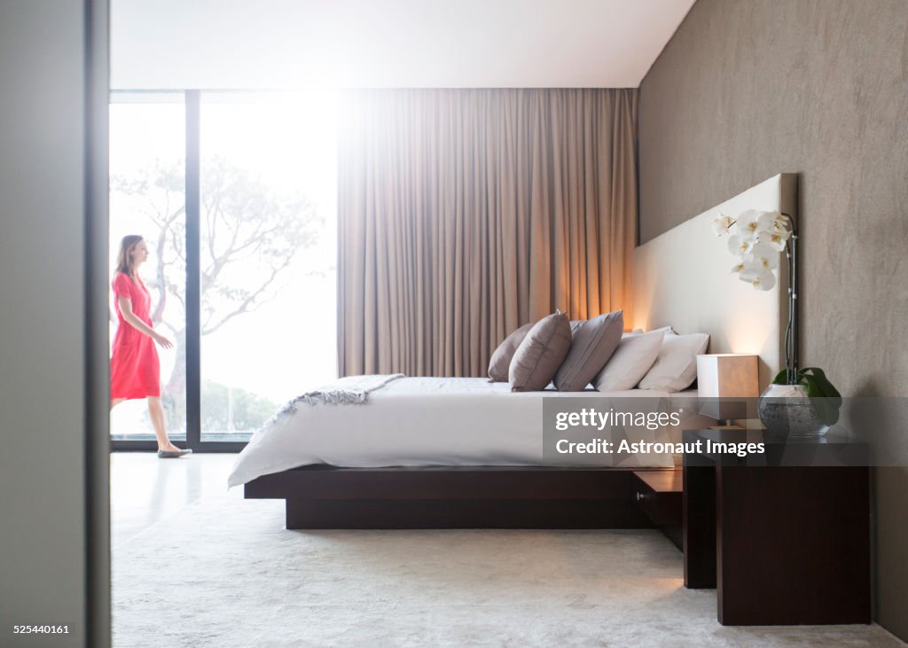 Woman in red dress walking through modern bedroom