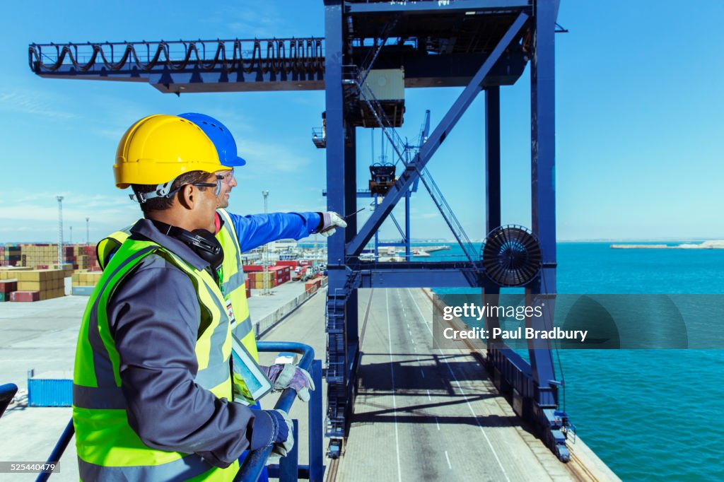 Worker and businessman examining cargo crane at waterfront