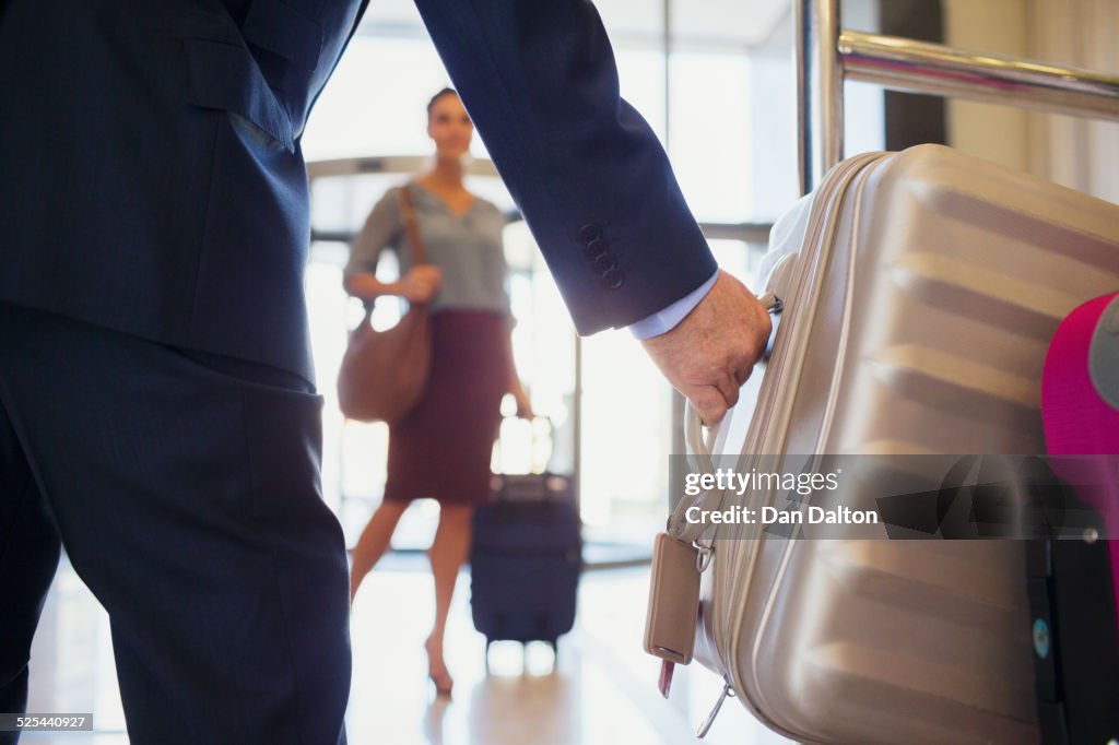 Primo piano di uomo che indossa la valigia d'argento che afferra la valigia d'argento, donna sullo sfondo