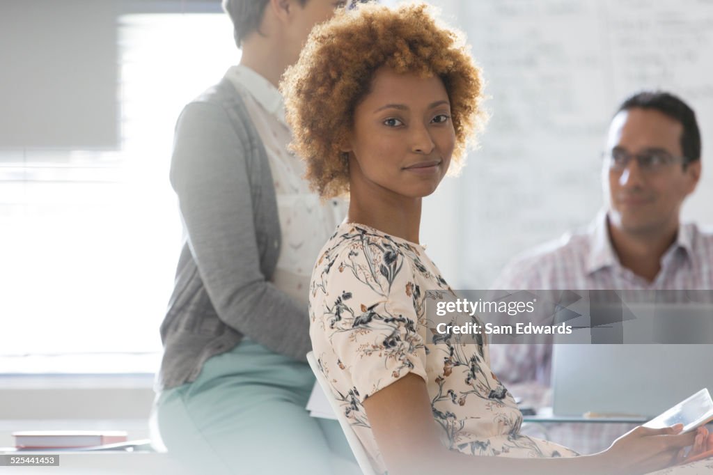 Portrait of businesswoman in office, colleagues in background