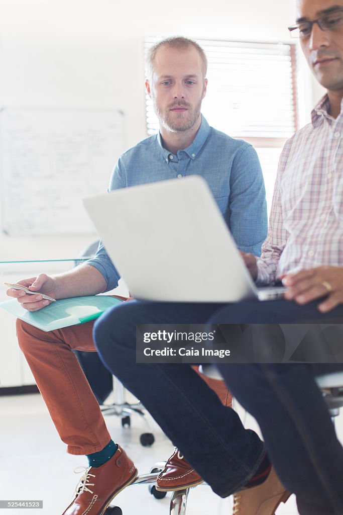 Two businessmen using laptop in office