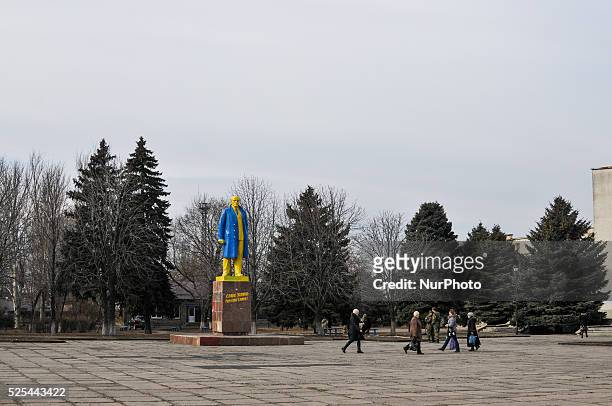 People pass by a statue of Vladimir Lenin painted a Ukrainian national flag yellow-blue color in the eastern town of Velyka Novoselivka, Donbas....