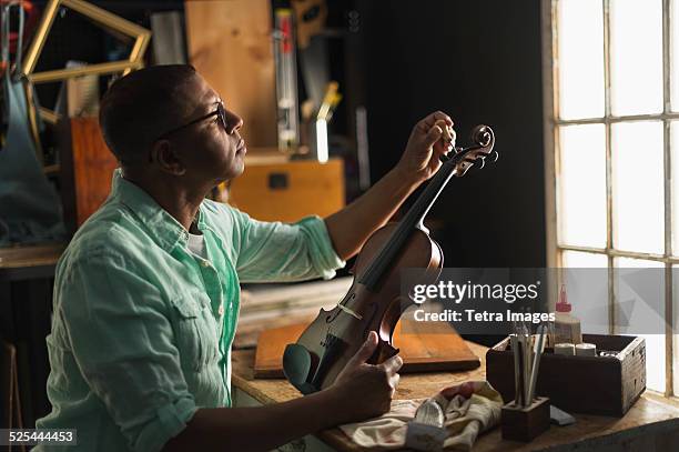 usa, new jersey, jersey city, mature man fixing violin in his workshop - make music day fotografías e imágenes de stock