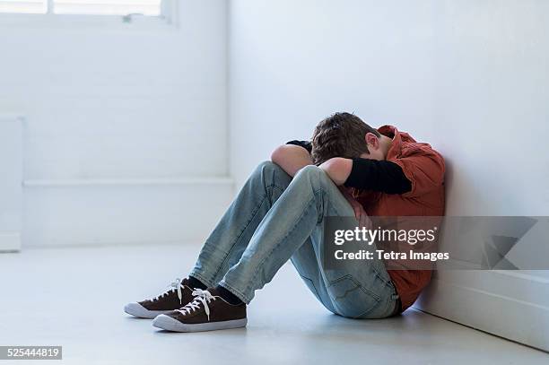 usa, new jersey, jersey city, teenage boy (16-17) sitting in hallway - depressie stockfoto's en -beelden