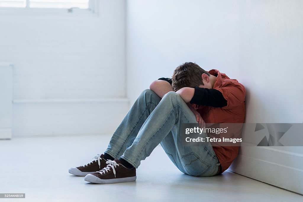 USA, New Jersey, Jersey City, Teenage boy (16-17) sitting in hallway