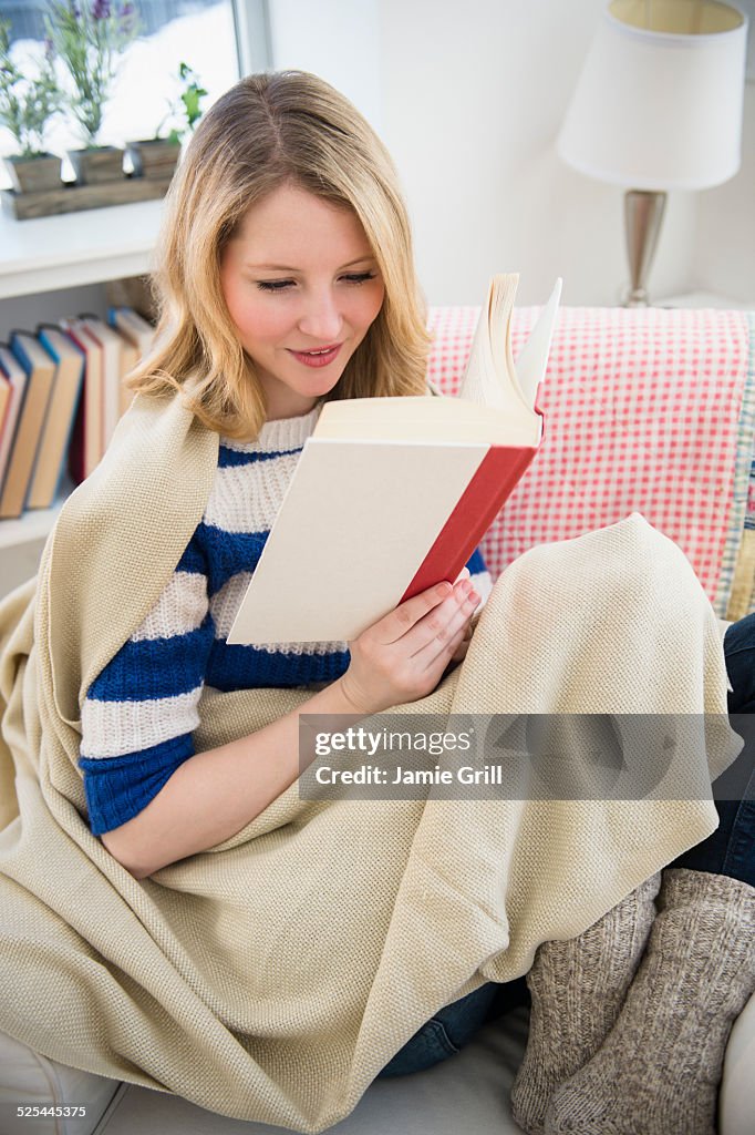 USA, New Jersey, Jersey City, Blond woman reading on sofa