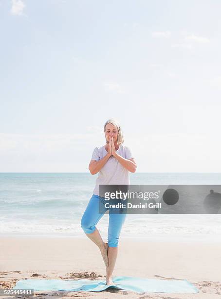 usa, florida, jupiter, senior woman practicing yoga on beach - jupiterimages stock pictures, royalty-free photos & images
