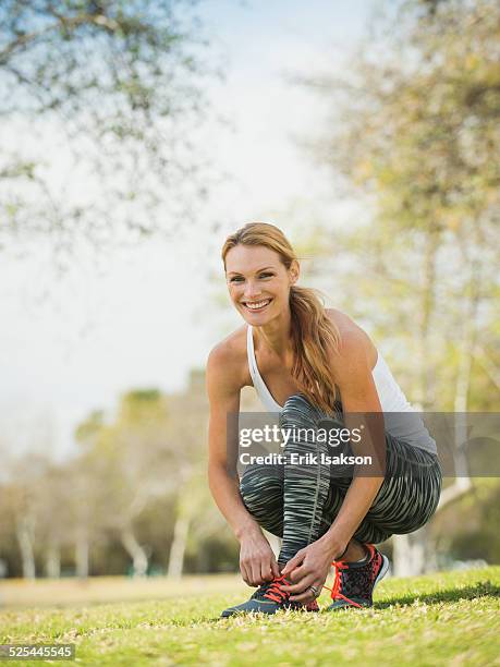 usa, california, irvine, woman in park tying shoe - sports footwear stock-fotos und bilder