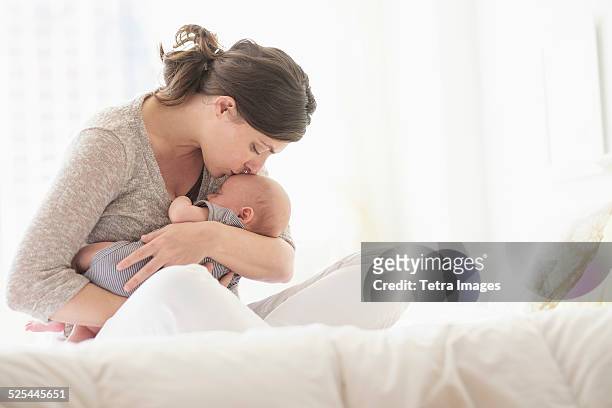 usa, new jersey, jersey city, mother kissing baby boy (2-5 months ) in bed - mutter baby stock-fotos und bilder