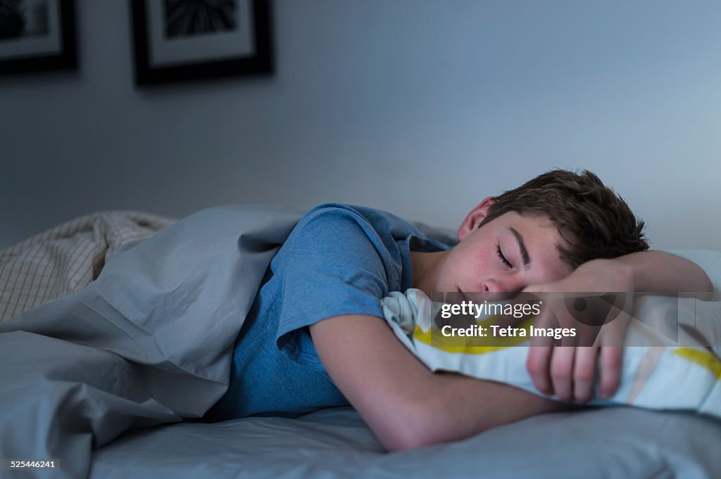 USA, New Jersey, Jersey City, Teenage boy (16-17) sleeping in bed