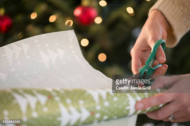 studio shot of female's hands cutting wrapping paper - ent stockfoto's en -beelden
