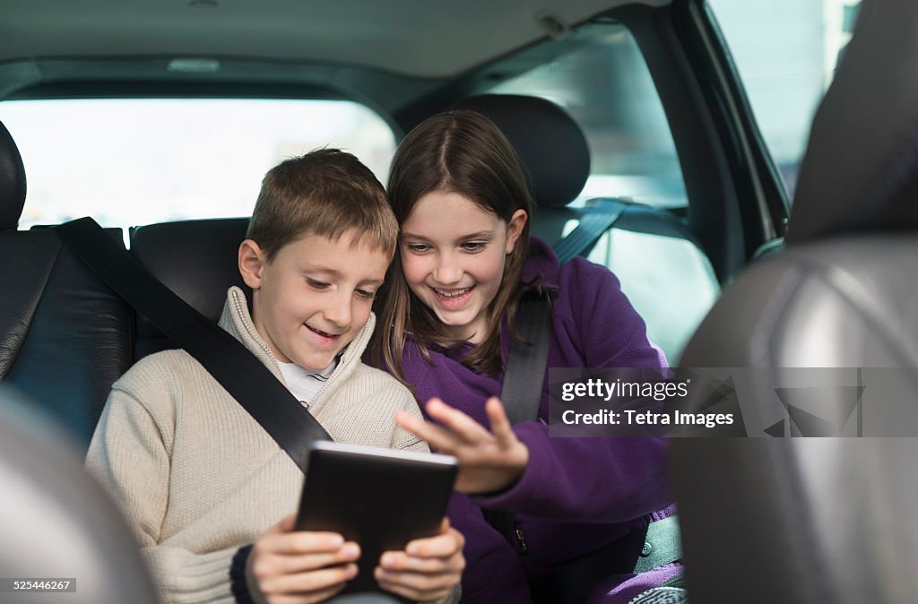 USA, New Jersey, Jersey City, Boy and girl (8-9, 10-11) using digital tablet in car