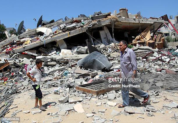 Palestinians next to the rubble of house destroyed after Israeli air strikes in Gaza City, 23 August 2014.