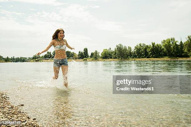 young woman running at waterside of rhine river - running shorts foto e immagini stock
